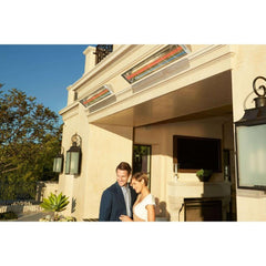 Man and woman standing outside a building with outdoor furniture with Infratech Outdoor Heaters